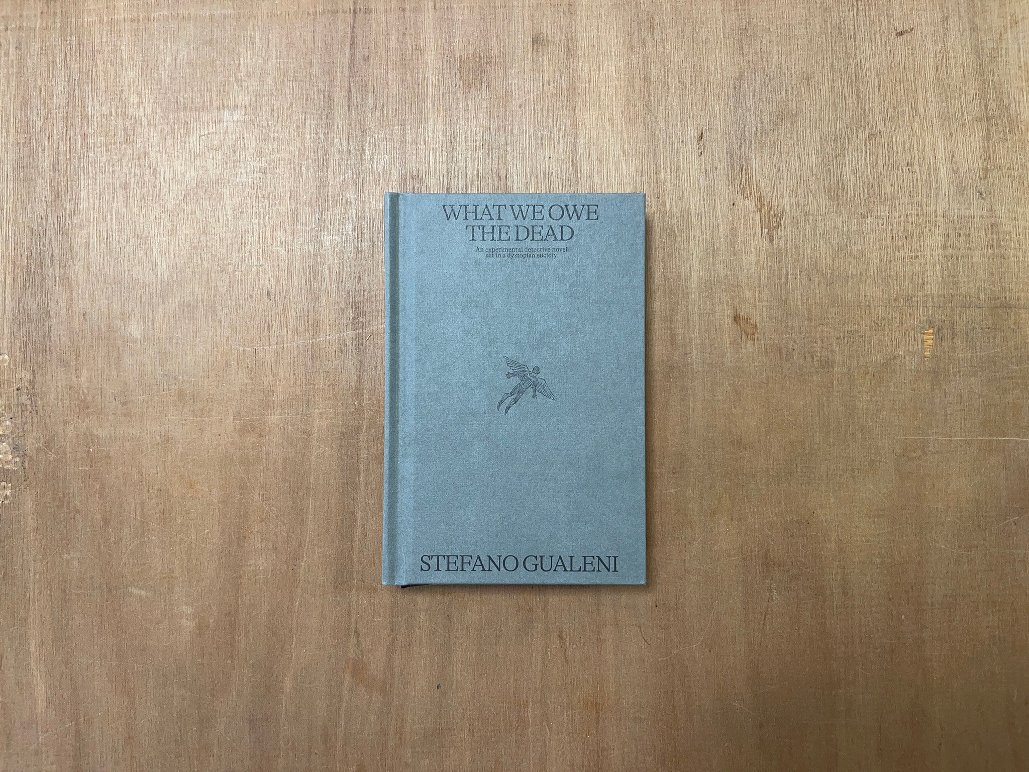 WHAT WE OWE THE DEAD: AN EXPERIMENTAL DETECTIVE NOVEL SET IN A DYSTOPIAN SOCIETY by Stefano Gualeni